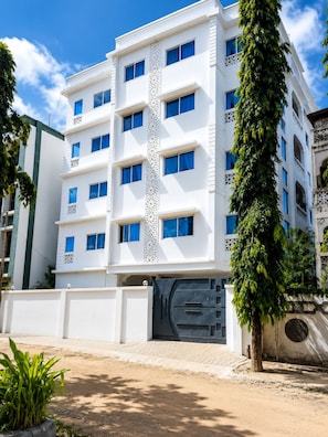 Un edificio de varios pisos con fachada blanca y ventanas azules.
