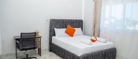 A bedroom with a bed, a desk, and a chair.