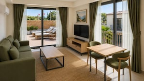 A modern living room with a sofa, a coffee table, a TV, and a dining area with chairs. - Ramada Resort By Wyndham Datca (Datca)
