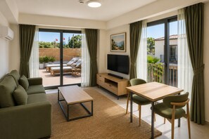 A modern living room with a sofa, a coffee table, a TV, and a dining area with chairs. - Ramada Resort By Wyndham Datca (Datca)