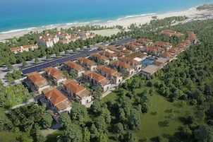 Un resort con varias edificaciones, una piscina y una playa al fondo.