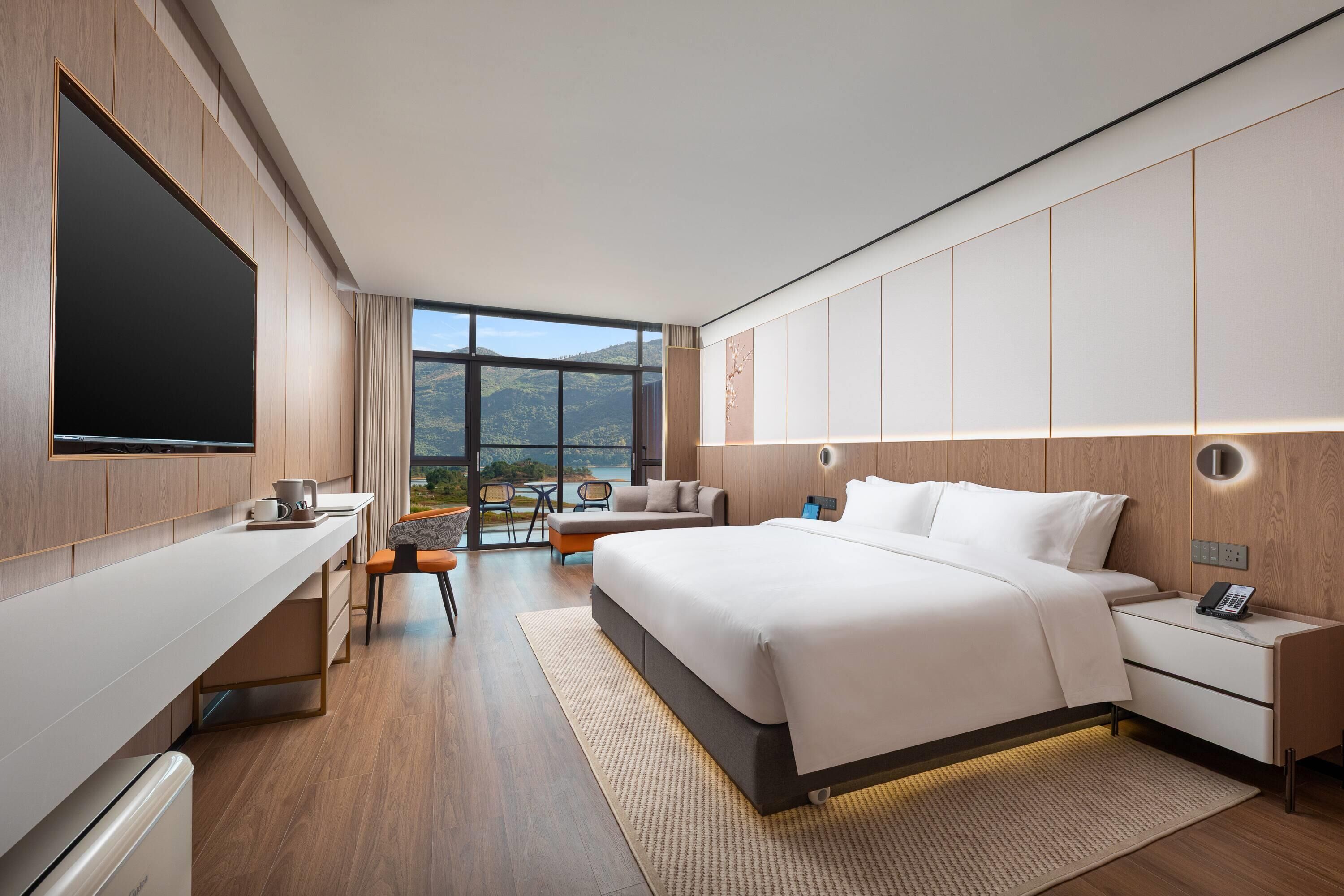 A modern hotel room with a large bed, a desk, and a TV.