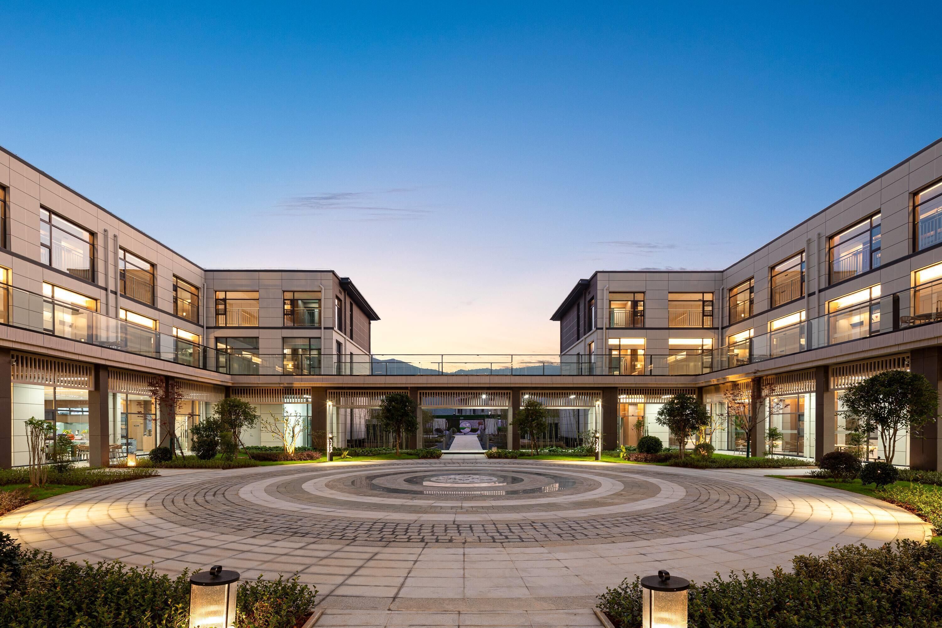 Un edificio moderno con un patio central, varios pisos y grandes ventanales.
