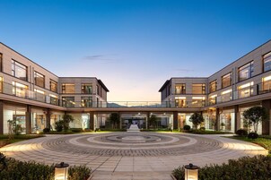 Un edificio moderno con un patio central, varios pisos y grandes ventanales.