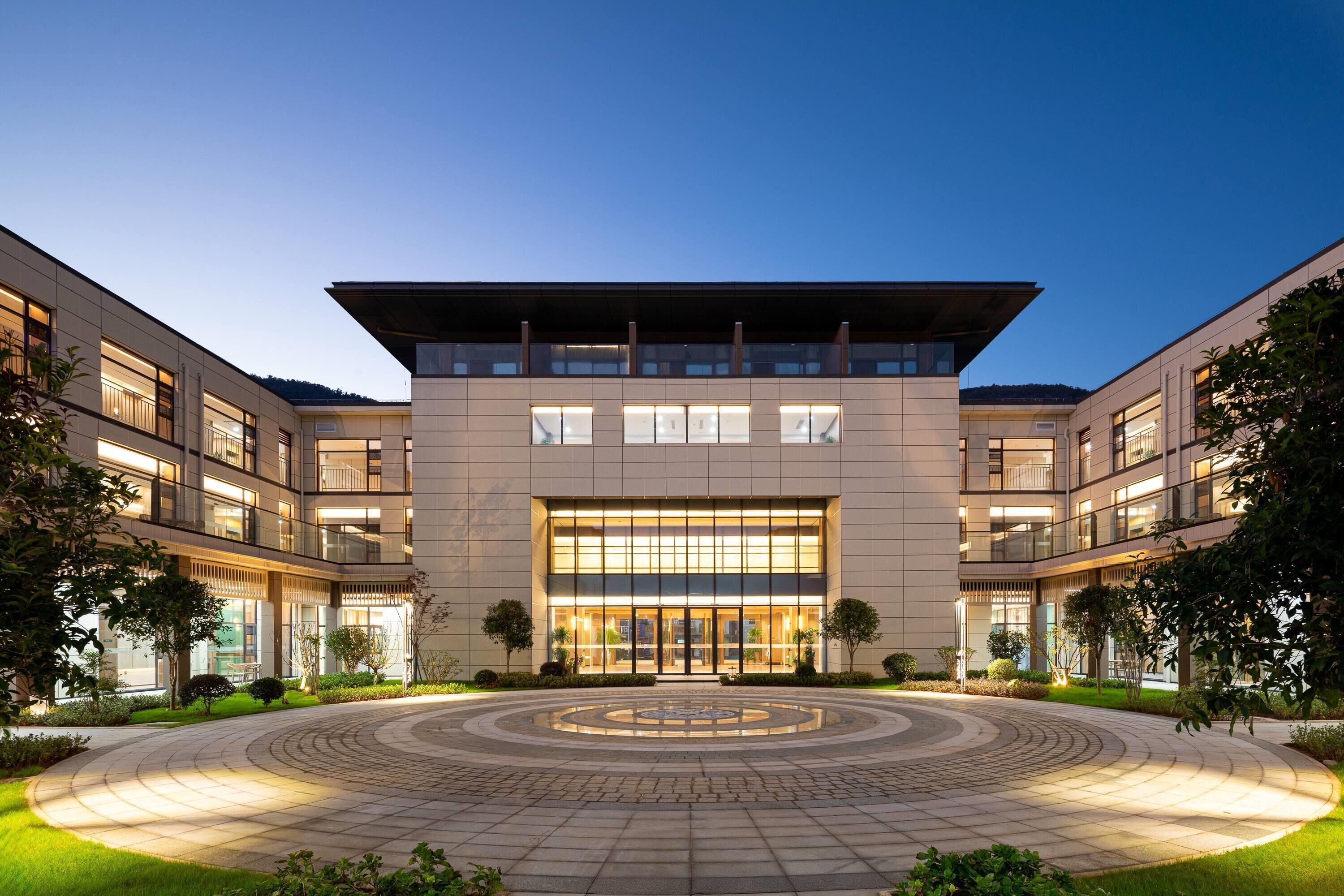 Un edificio moderno con un patio central, varios pisos y grandes ventanales.