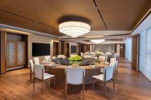 A spacious dining area with a round table, white chairs, and a central floral arrangement.