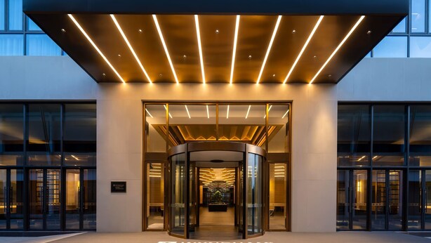 Una entrada de hotel moderna con puerta giratoria y fachada de vidrio.