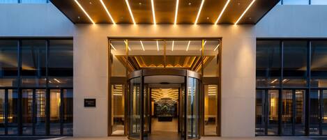 A modern hotel entrance with a revolving door and glass facade.