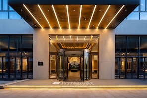 Una entrada de hotel moderna con puerta giratoria y fachada de vidrio.