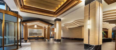 A spacious lobby with a reception desk, seating area, and a large window with a view.