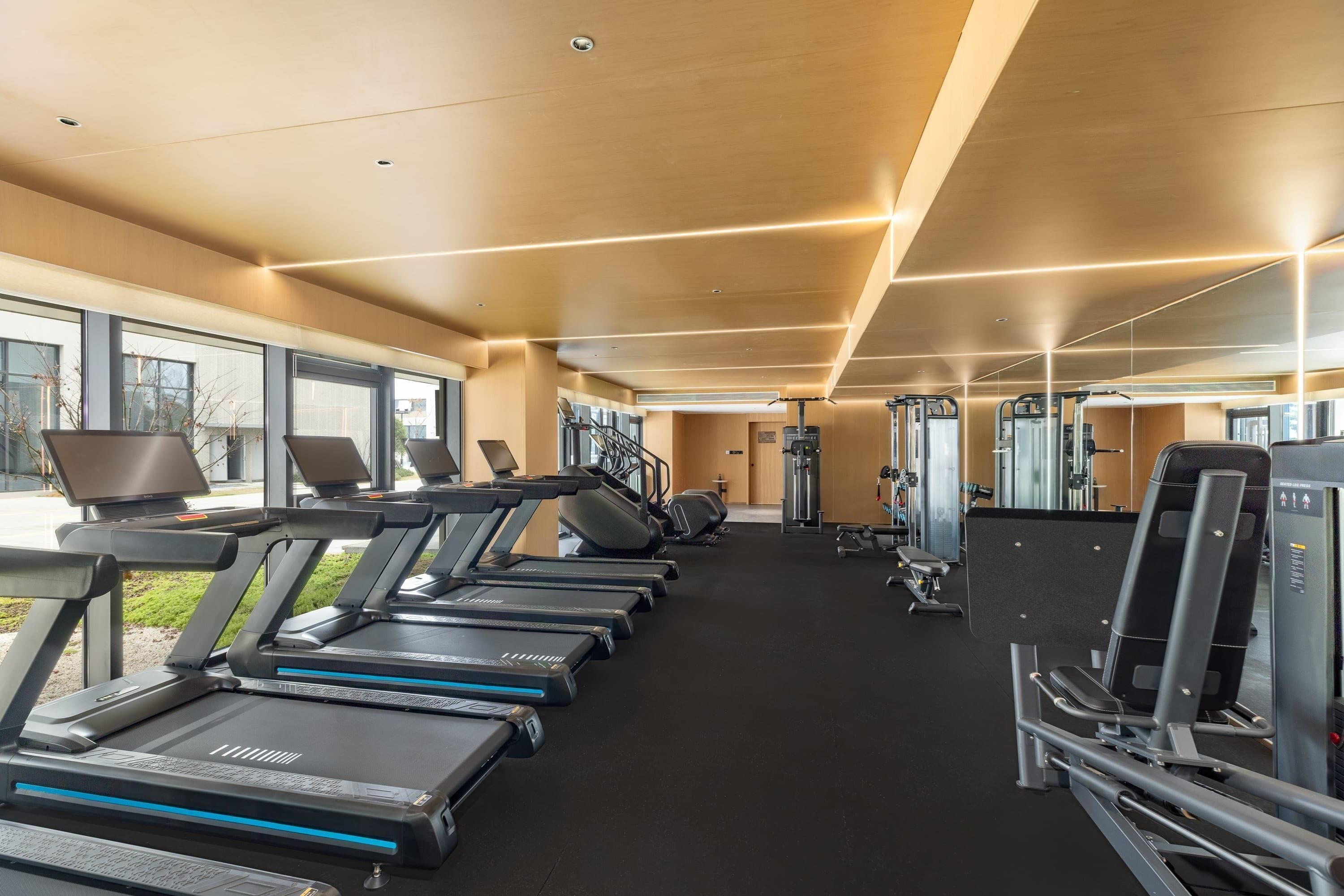 Una palestra con tapis roulant, macchinari per pesi e tappetini da ginnastica.