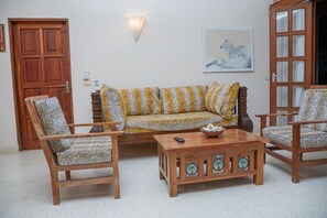 A living room with a sofa, two armchairs, a coffee table, and a wooden door. - Tropical 2BR Malindi Condo | Pool & Balcony Views ❤️ (Malindi)