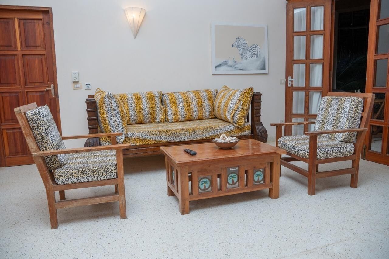 A living room with a sofa, two armchairs, a coffee table, and a wooden cabinet.