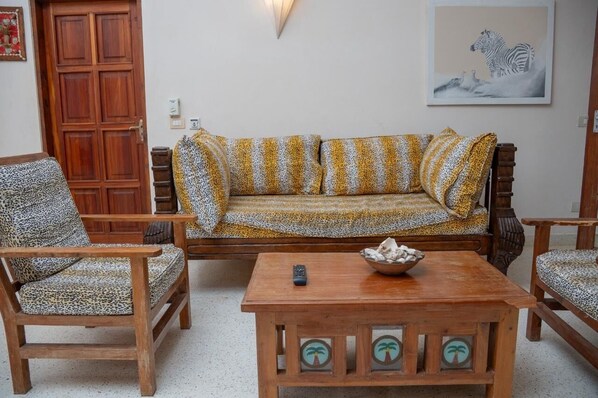 A living room with a sofa, two armchairs, a coffee table, and a wooden door.