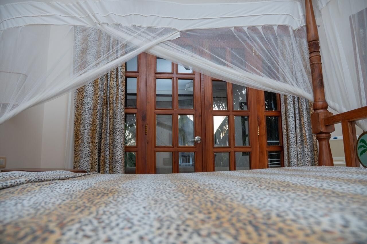 A bedroom with a bed, a wooden door, and a window.