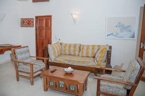 A living room with a sofa, two armchairs, a coffee table, and a wall-mounted light fixture.