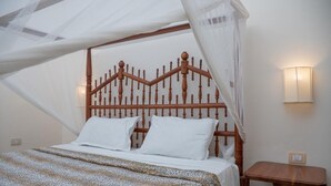 Een bed met hemel, een nachtkastje en een wandlamp.