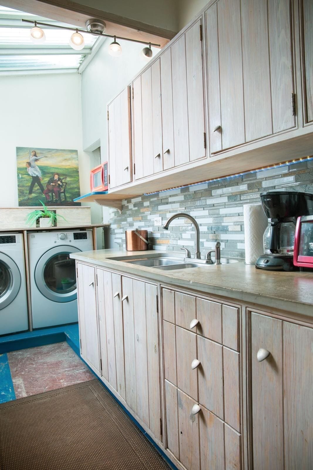 A laundry area with a washing machine, dryer, and a sink with a faucet.