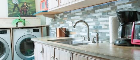 A laundry area with a washing machine, dryer, and a sink with a faucet.