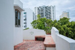 A narrow outdoor corridor with a tiled floor, surrounded by white walls and a red brick structure. - Step to the beach /Beautiful Penthouse + Private Terrace (San Juan)
