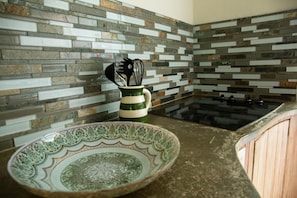 A kitchen with a modern design, featuring a patterned backsplash and a black stovetop. - Step to the beach /Beautiful Penthouse + Private Terrace (San Juan)