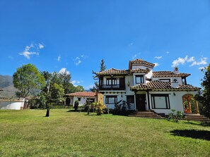 A two-story building with a tiled roof, a front entrance with steps, and a well-maintained lawn.