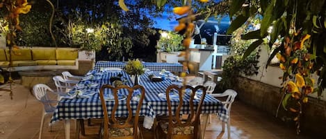 An outdoor dining area with checkered tablecloths, wooden chairs, and a tiled floor.