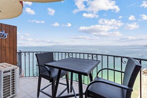 Un balcone con tavolo e due sedie che si affaccia su un corpo d'acqua.