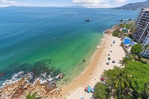 Un hotel sulla costa con spiaggia, piscina e vista mare.