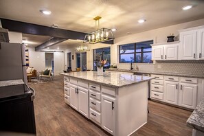 A modern kitchen with white cabinetry, a large island, and pendant lighting.