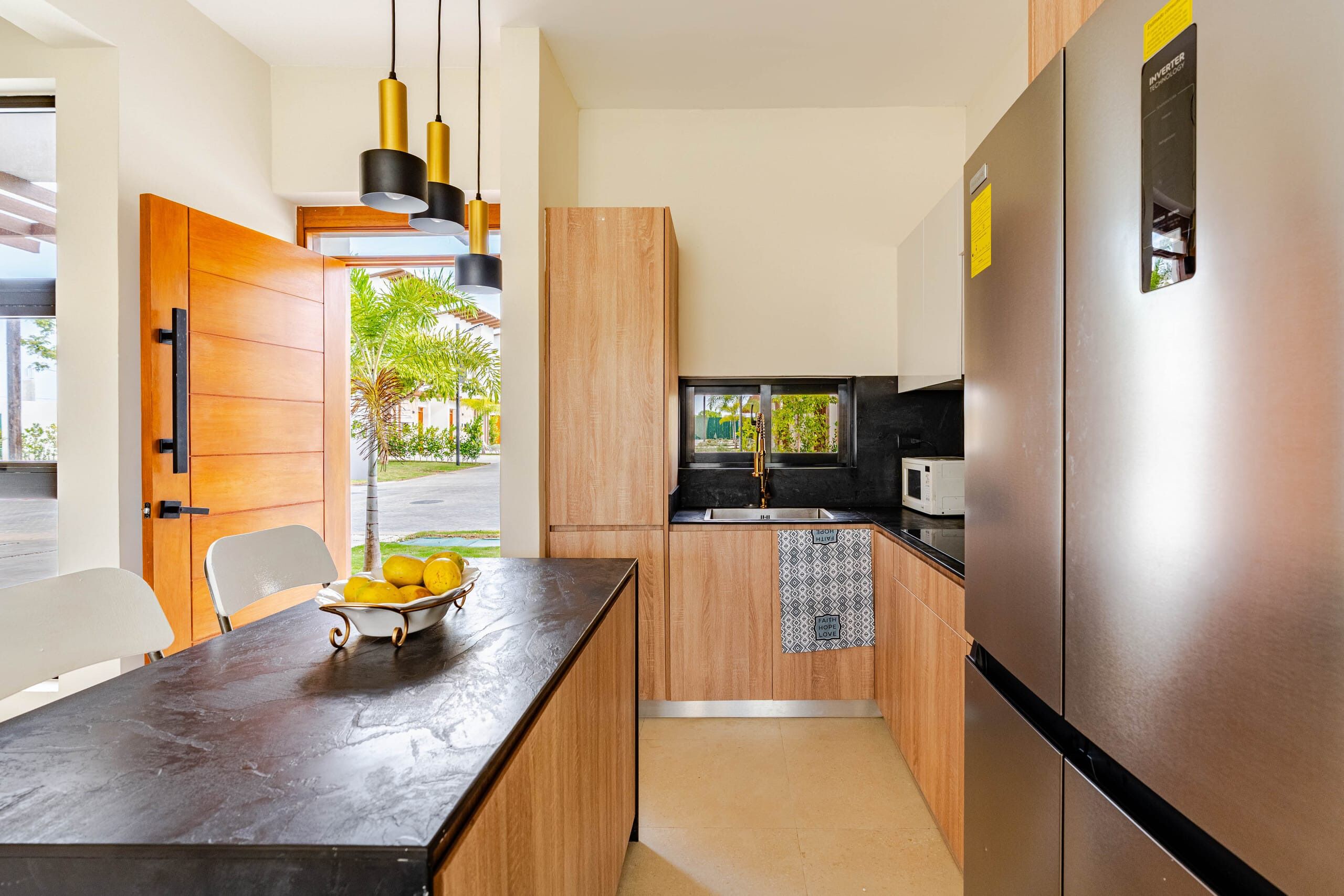 A modern kitchen with a wooden cabinet, a black countertop, and a stainless steel refrigerator.
