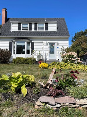 A two-story house with a dark roof, white siding, and a front porch.
