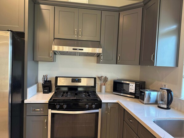 A kitchen with a stove, microwave, toaster, and stainless steel sink. - 3BR Townhouse for Groups, Near Disneyland (Garden Grove)