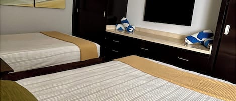 Habitación de hotel con dos camas, un televisor de pantalla plana, un cuadro en la pared y un armario.