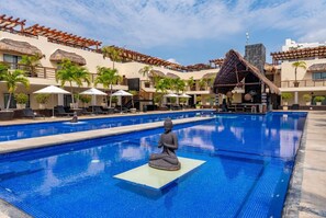 A swimming pool with a Buddha statue in the center, surrounded by lounge chairs and umbrellas. - Aldea Thai PH - Private Oceanfront Pool - Entire condo in Playa del Carmen (Playa del Carmen)