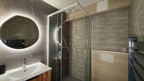 A modern bathroom with a glass-enclosed shower, a round mirror, and a wooden vanity. - Balcony, tv, ski locker, 50m², Chamrousse (Chamrousse)