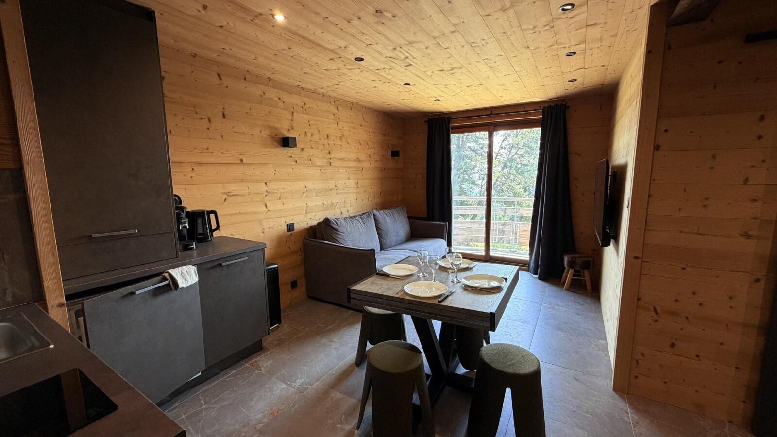 A compact kitchen with a refrigerator, a coffee maker, and a dining table set for four.