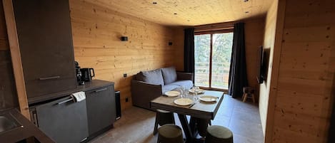 A compact kitchen with a refrigerator, a coffee maker, and a dining table set for four.