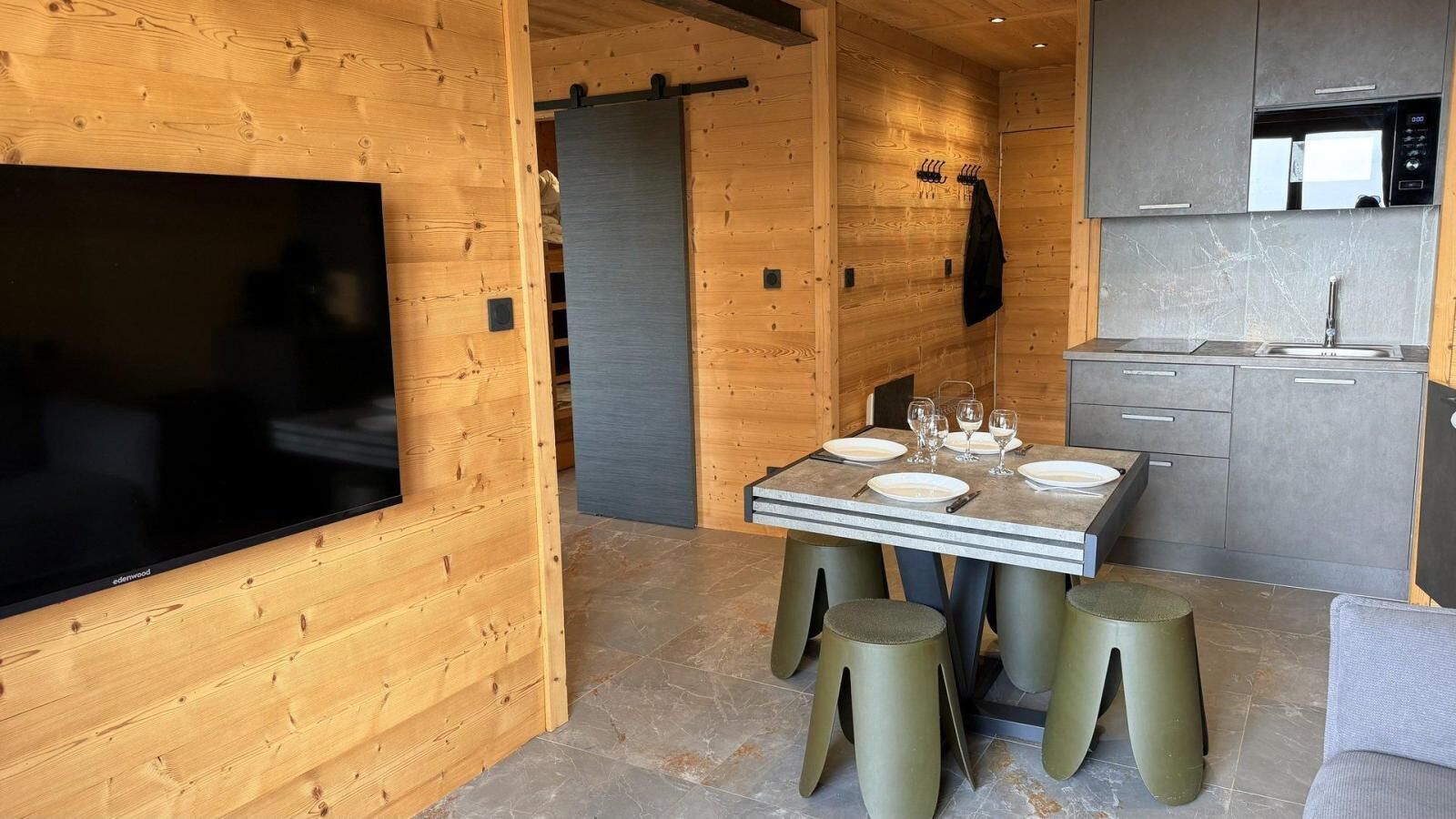 Une cuisine moderne avec des meubles gris, un four à micro-ondes encastré et un coin repas avec une table dressée pour quatre personnes.