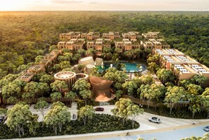 Ein Resort mit mehreren Gebäuden, einem zentralen Pool und umgebender Bepflanzung.