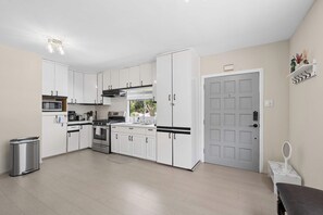 A modern kitchen with white cabinets, stainless steel appliances, and a view to the outside.