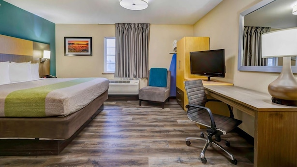 Une chambre d’hôtel équipée d’un lit, d’un bureau, d’une chaise, d’une télévision et d’un grand miroir.