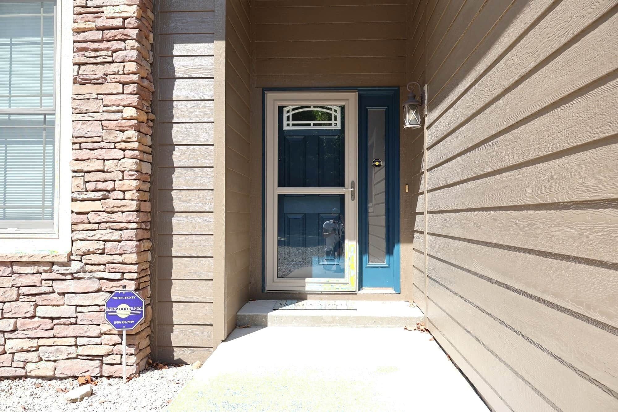 Une maison avec une façade en pierre, une porte bleue et un petit porche.