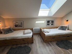 A room with two wooden beds, a skylight, and a small TV. - 50m from ski slopes, 4th floor, balcony, tv, ski locker, 91m², Valmorel (Les Avanchers-Valmorel)