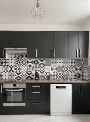 Una cocina moderna con armarios oscuros, un salpicadero con diseño y un lavavajillas.