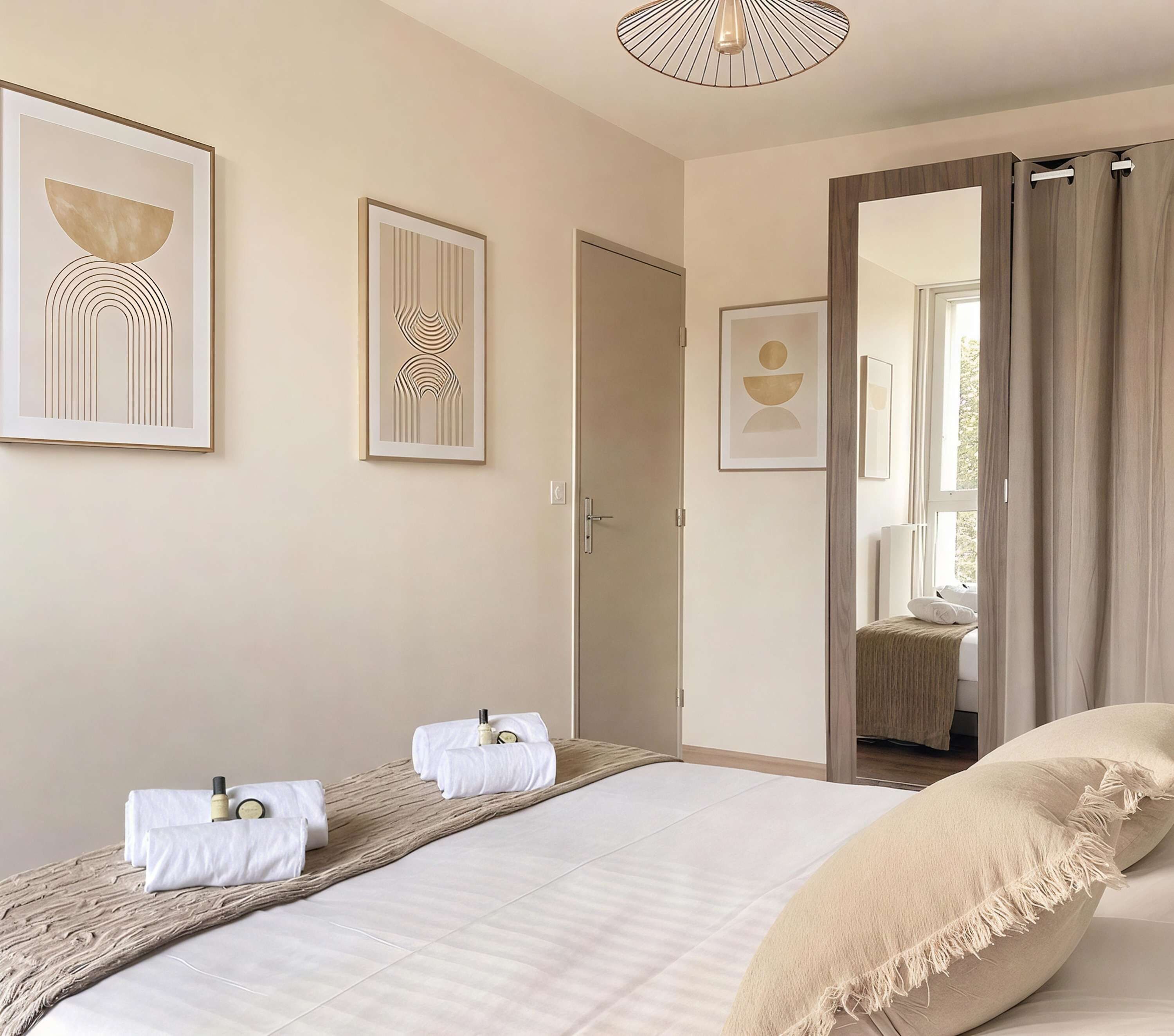A bedroom with a bed, two bedside tables, a door, and framed artwork on the wall.