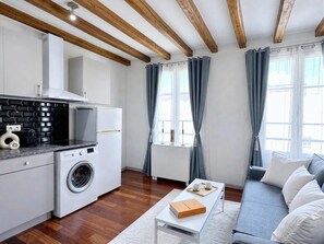 Una cocina moderna con lavadora, una mesa de centro con un libro y un sofá gris.