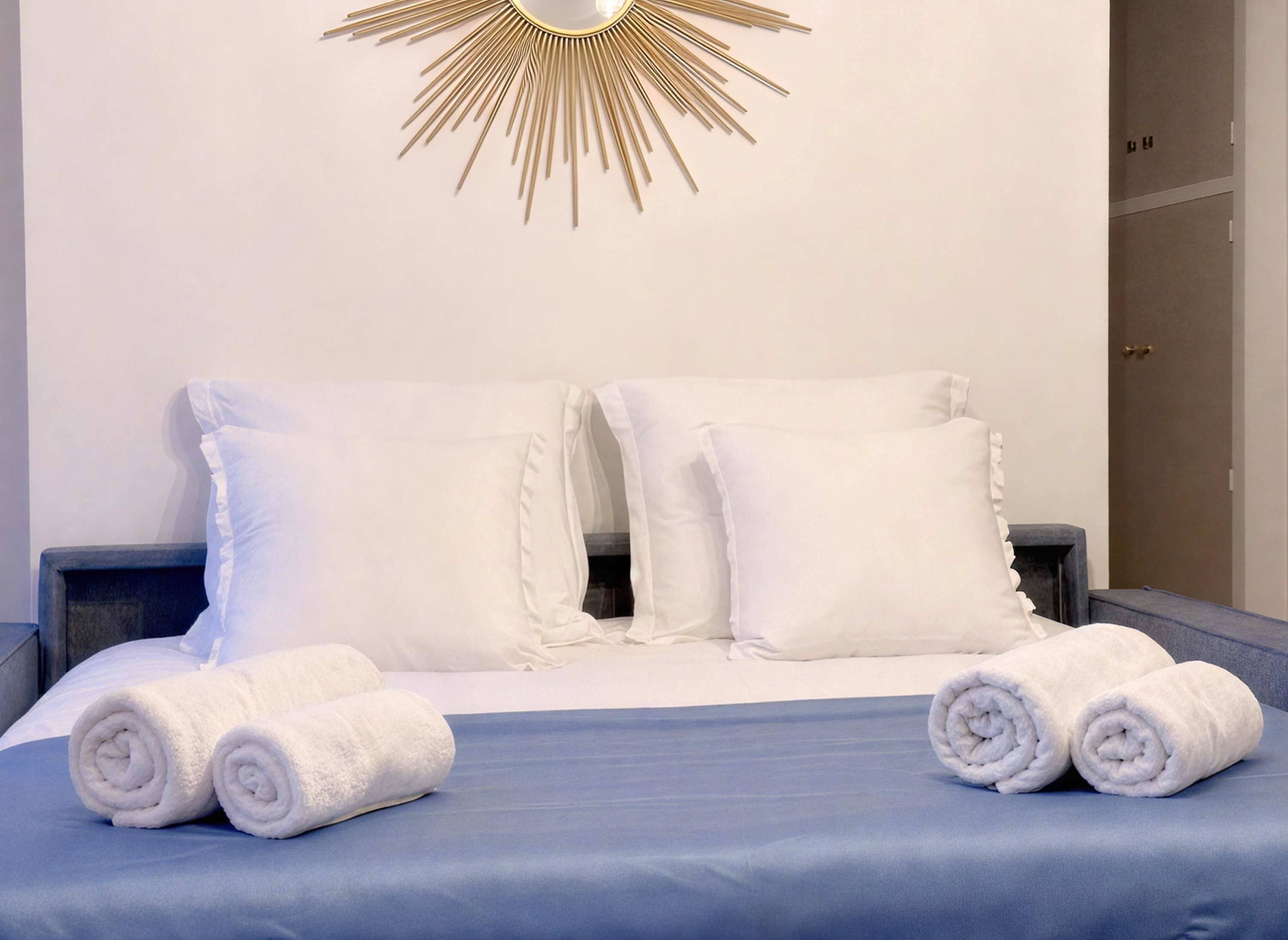 Een hotelkamer met een bed, twee kussens en twee opgerolde handdoeken.