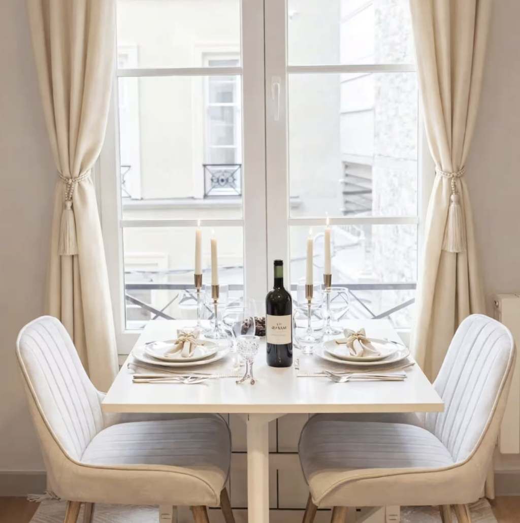 Een eettafel gedekt voor twee personen, met kaarsen, een fles wijn en een glas.