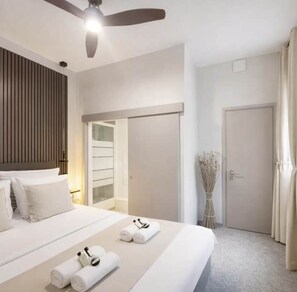 A hotel room with a bed, a ceiling fan, a door, and a vase with dried flowers. - Family Appartment off Champs Elysees by Melvane (Paris)